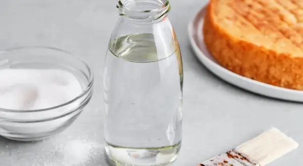 Zutaten für zuckersirup selber machen: Zucker, Wasser in Flasche, Pinsel und ein Kuchenboden.