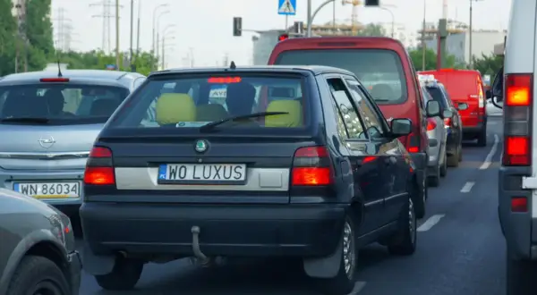 Korek uliczny, gdzie widać samochody z indywidualnymi tablicami rejestracyjnymi, np. "WO LUXUS".
