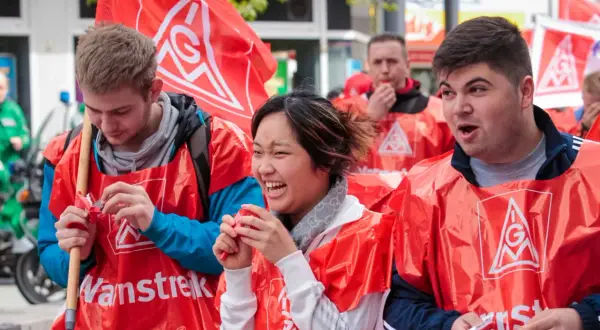 Junge Leute in roten Westen mit IG Metall Logo bei einer Demonstration. Sie wirken engagiert und hoffnungsvoll für die jav Wahlen.