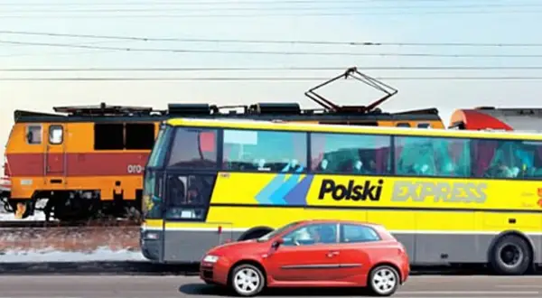Pociąg, żółty autobus "Polski Express" i czerwony samochód jadą obok siebie, jakby na trasie katowice-kraków.