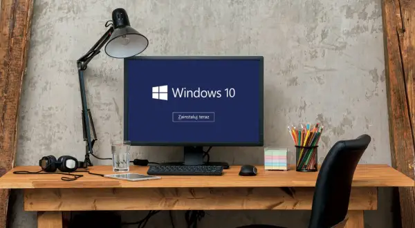 Biurko z komputerem Windows 10, lampką, słuchawkami i szkłem wody. Zastanawiasz się, jak wyłączyć komputer?