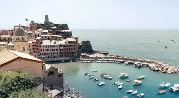 Bunte Häuser am Hafen von Cinque Terre, Italien, mit vielen Booten im türkisfarbenen Wasser.