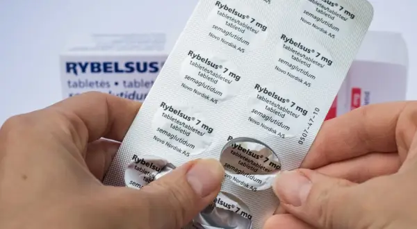 Dłonie trzymają opakowanie leku Rybelsus 7 mg, zawierającego tabletki z semaglutydem.