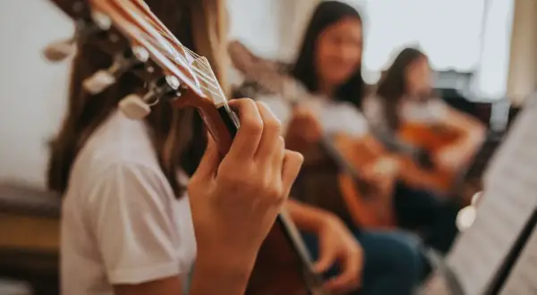 Dziewczyny ćwiczą grę na gitarach w szkole muzycznej.