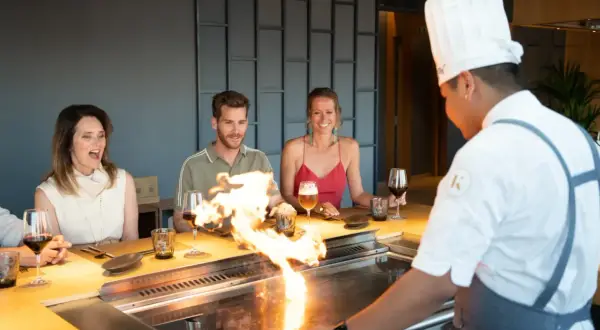 Chef prepara teppanyaki que es una experiencia culinaria interactiva. Los comensales disfrutan del espectáculo de fuego y la comida.