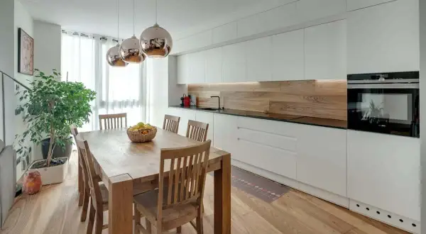 Tavolo in legno con sedie, ideale per chi vuole ristrutturare cucina. Illuminazione moderna e mobili bianchi.
