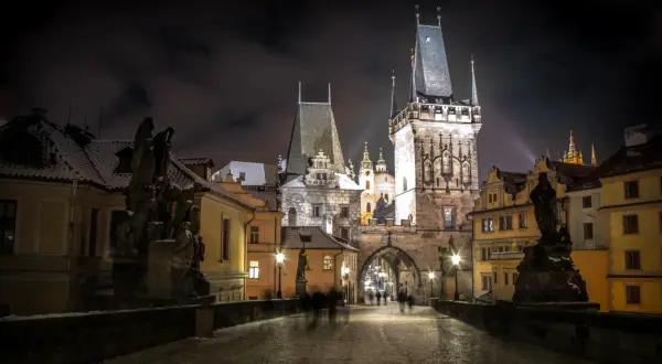 Most Karola w Pradze nocą, ośnieżony, z wieżami i rzeźbami. Idealne miejsce na wycieczki objazdowe po Europie.