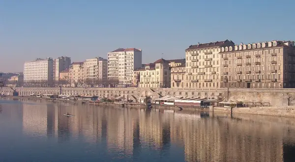 I **murazzi** di Torino si specchiano nel fiume, con palazzi storici e moderni che si affacciano sulla riva.