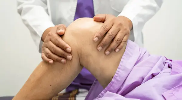 Lekarz bada kolano pacjenta, podejrzewając zerwane ACL. Wyniki rezonansu pomogą w diagnozie.
