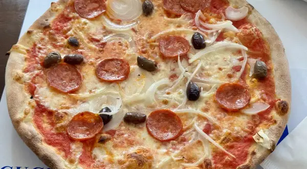 Eine köstliche Pizza mit Salami, Zwiebeln und Oliven, frisch aus i due forni.