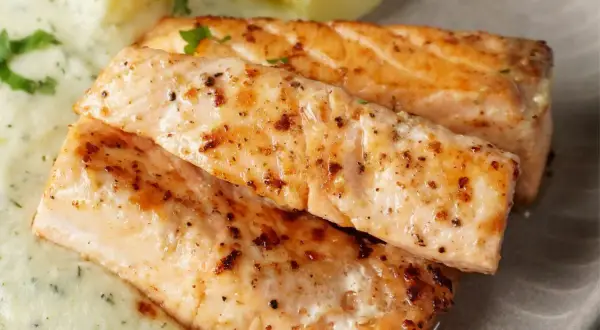 Zwei saftige Lachsfilets, perfekt gebraten, mit cremiger Sauce und Kartoffeln. Ein tolles Gericht für Lachs Rezepte.