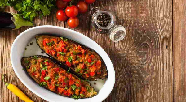 Melanzane a barchetta ripiene, pronte per essere gustate. Ingredienti freschi e un tocco di peperoncino giallo.