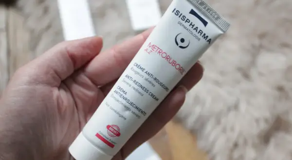 Crème anti-rougeurs pour la rosacée, contenant de l'acide azélaïque. Le tube Metroruboril A.Z d'Isispharma est tenu dans une main.