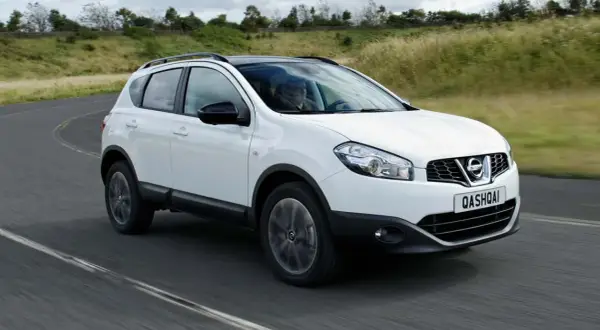 Vit Nissan Qashqai kör på en kurvig väg. En förare syns bakom ratten. Kanske ett problem med bilen?
