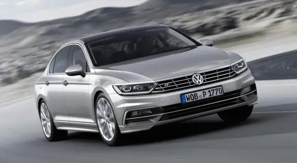 Silver Passat GTR glider fram på en väg med berg i bakgrunden.