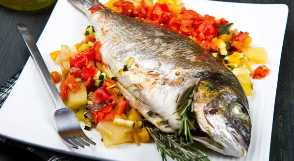 Dorada a la espalda, horneada con verduras y hierbas frescas, lista para disfrutar.