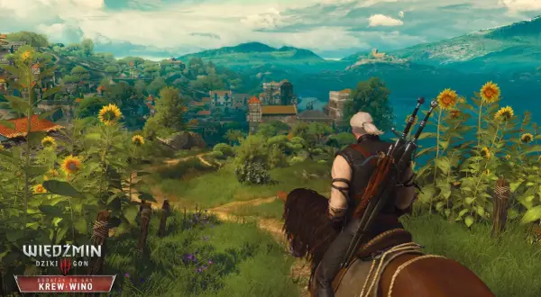 Geralt na koniu podziwia krajobraz z kwitnącymi słonecznikami, w oddali widać miasteczko. W tle góry i jezioro.