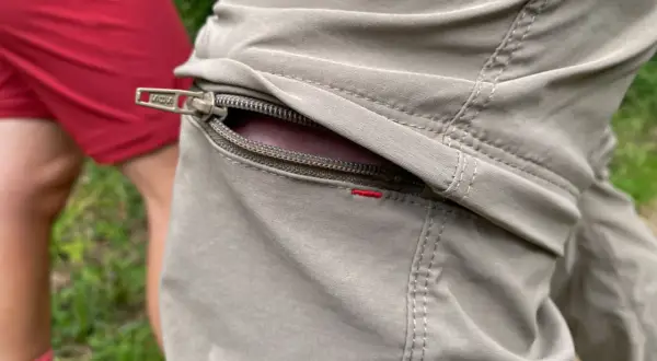 Detailaufnahme einer beige Wanderhose mit Reißverschlusstasche. Perfekt, welche Hose zum Wandern?