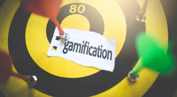 Rzutki na tarczy symbolizują cel, a napis "gamification" wskazuje na strategię grywalizacji w biznesie.