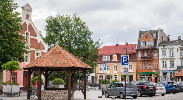 Rynek w Starogardzie Gdańskim, stolicy Kociewia, z drewnianą studnią i kolorowymi kamienicami.