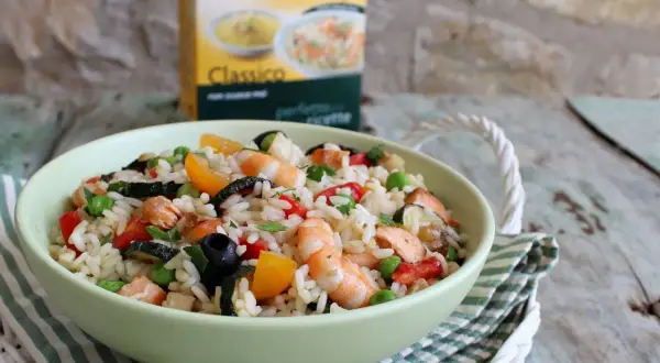 Un'appetitosa insalata di riso con pesce, gamberetti, verdure e olive, pronta per essere gustata.