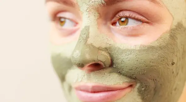 Primo piano di un volto con maschera all'argilla verde. Scopri a cosa serve l'argilla verde per la tua pelle.