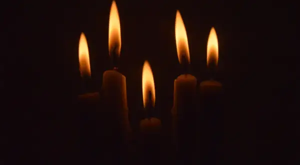 Płomienie świec w ciemności, symbolizujące zablokowaną żałobę.