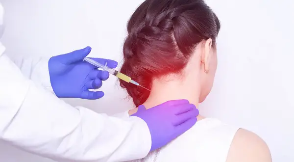 Avis sur infiltration cervicale C5-C6 : un médecin injecte un traitement dans le cou d'une patiente, soulageant une douleur localisée.