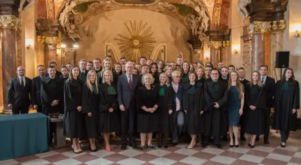 Grupa prawników w togach stoi w ozdobnym wnętrzu.
