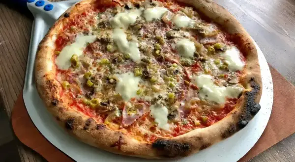 Gorąca pizza salami z roztopionym serem, oliwkami i pieczarkami, gotowa do podania.