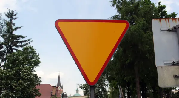 Żółty trójkątny znak drogowy informuje o ustąpieniu pierwszeństwa.