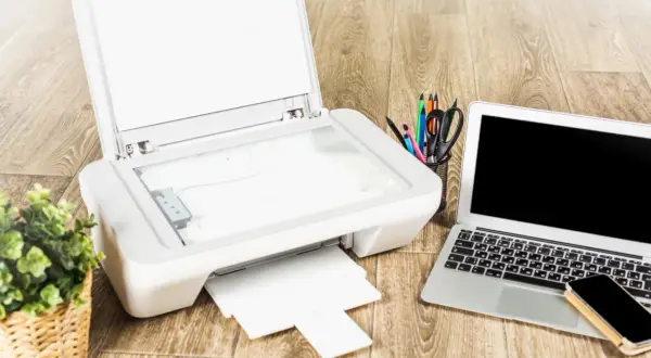 Drukarka, laptop i telefon leżą na drewnianym biurku. Zastanawiasz się, czy można podłączyć drukarkę do telefonu?