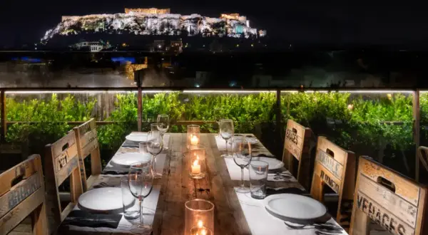 Gedeckter Tisch mit Blick auf die beleuchtete Akropolis bei Nacht.