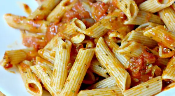 Pyszny makaron penne z aromatycznym sosem pomidorowym, posypany ziołami. Idealny na szybki obiad.