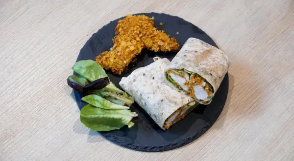 Pyszny kebab w tortilli, idealnie zawinięty, z chrupiącymi kawałkami kurczaka i świeżą sałatką.