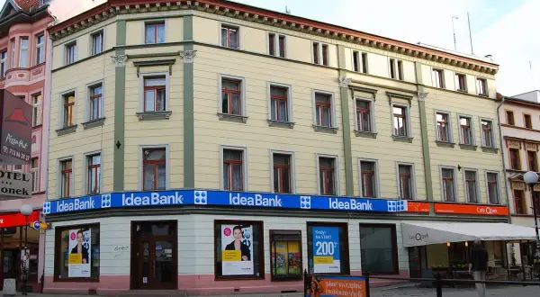 Elegancki budynek z szyldami Idea Bank i Cafe Qbek. W witrynach banku reklamy kredytów i usług.