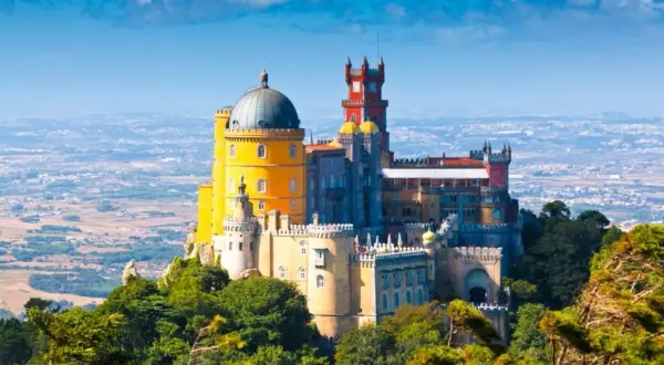 El Pazo da Pena, un palacio de cuento de hadas con cúpulas y torres coloridas, se alza majestuoso sobre una colina verde.