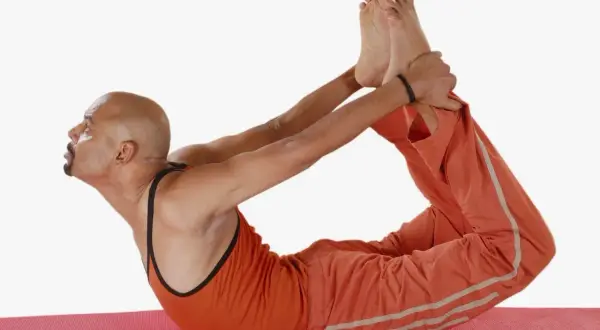 Hombre en postura del arco yoga, estirando su espalda y piernas.