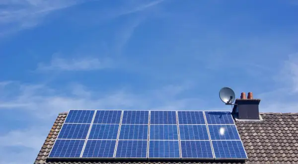 Panele fotowoltaiczne na dachu domu, symbolizujące długą żywotność i ekologiczne pozyskiwanie energii.