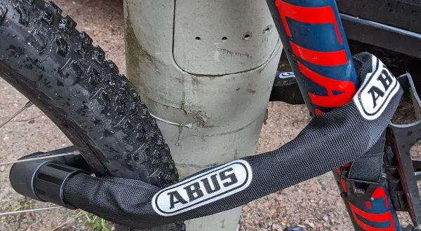 Fahrrad diebstahlschutz: Ein ABUS Kettenschloss sichert das Rad an einem Pfosten.