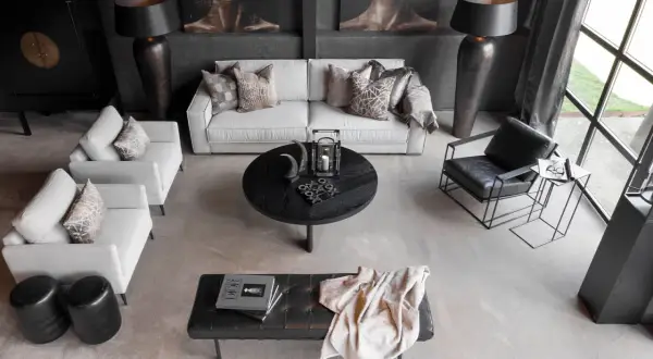 En modern lounge med soffa, fåtöljer och ett runt soffbord. En stilren och maskulin inredning med fokus på mörka toner och geometriska former.