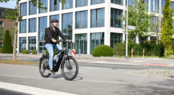 Mann fährt mit E-Bike durch eine moderne Stadt in Deutschland.