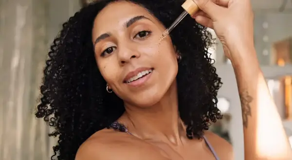 Frauen mit lockigem Haar tragen ein Serum mit Peptiden auf, um ihre Haut mit Feuchtigkeit zu versorgen.
