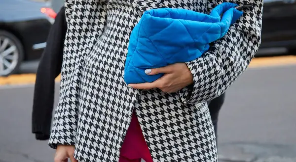 Elegancka marynarka w pepitkę, zestawiona z jaskrawymi różowymi spodniami i błękitną kopertówką, tworzy modne stylizacje.