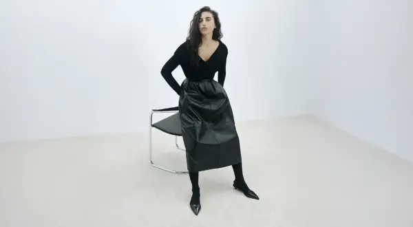 Elegancka czarna spódnica z ekoskóry, zestawiona z czarnym swetrem i butami. Stylowe czarna spódnica stylizacje.