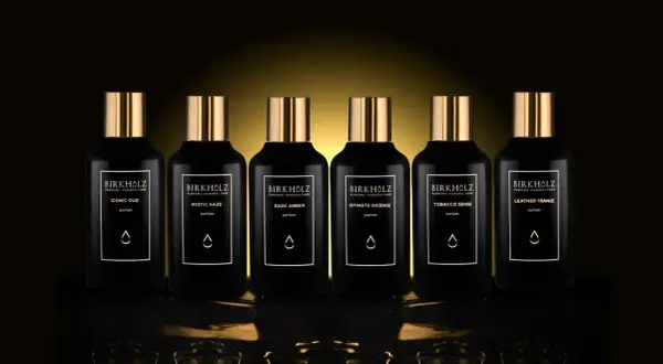 Sześć czarnych flakonów perfum Birkholz z złotymi nakrętkami. Jeden z nich to "Dark Amber", o głębokim, **dark amber** kolorze.