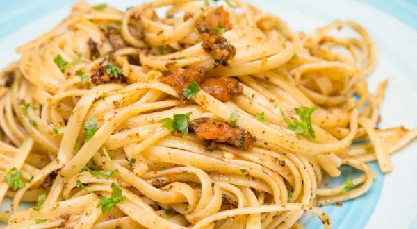 Linguine condite con un saporito sugo ai ricci di mare, guarnite con prezzemolo fresco.