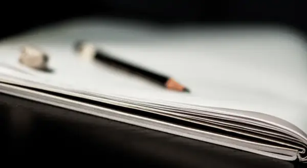 Otwarta książka z ołówkiem i gumką do ścierania.