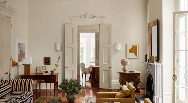 Soggiorno elegante con divani color ocra e un raffinato abbinamento colori crema. Tavolino in legno grezzo e tappeto decorato.