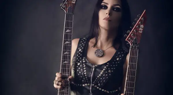 Marta Gabriel, wokalistka i gitarzystka, z dwoma gitarami elektrycznymi w skórzanej kamizelce z ćwiekami.